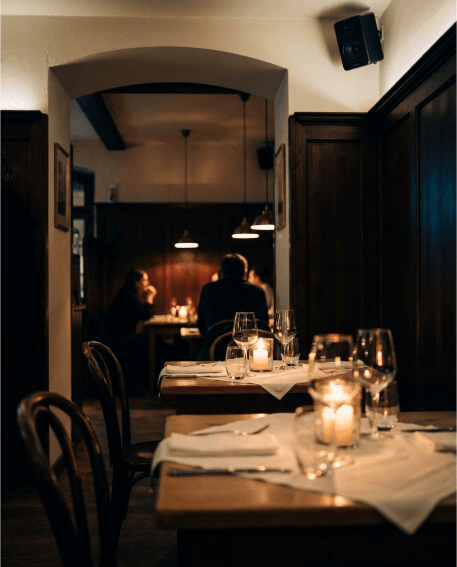 Restaurant am Abend: Kerzenlicht, gedeckte Tische, Deckenlautsprecher