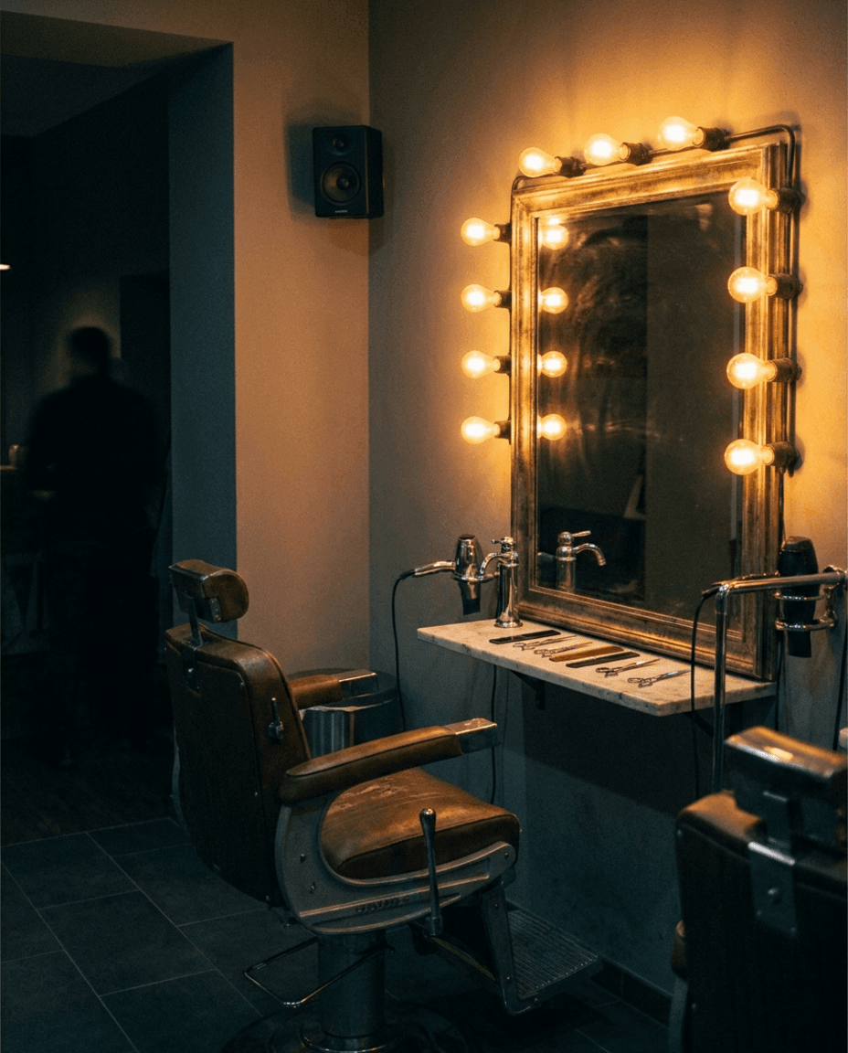 Friseursalon am Abend: Barberstuhl, beleuchteter Spiegel, Lautsprecher an der Wand